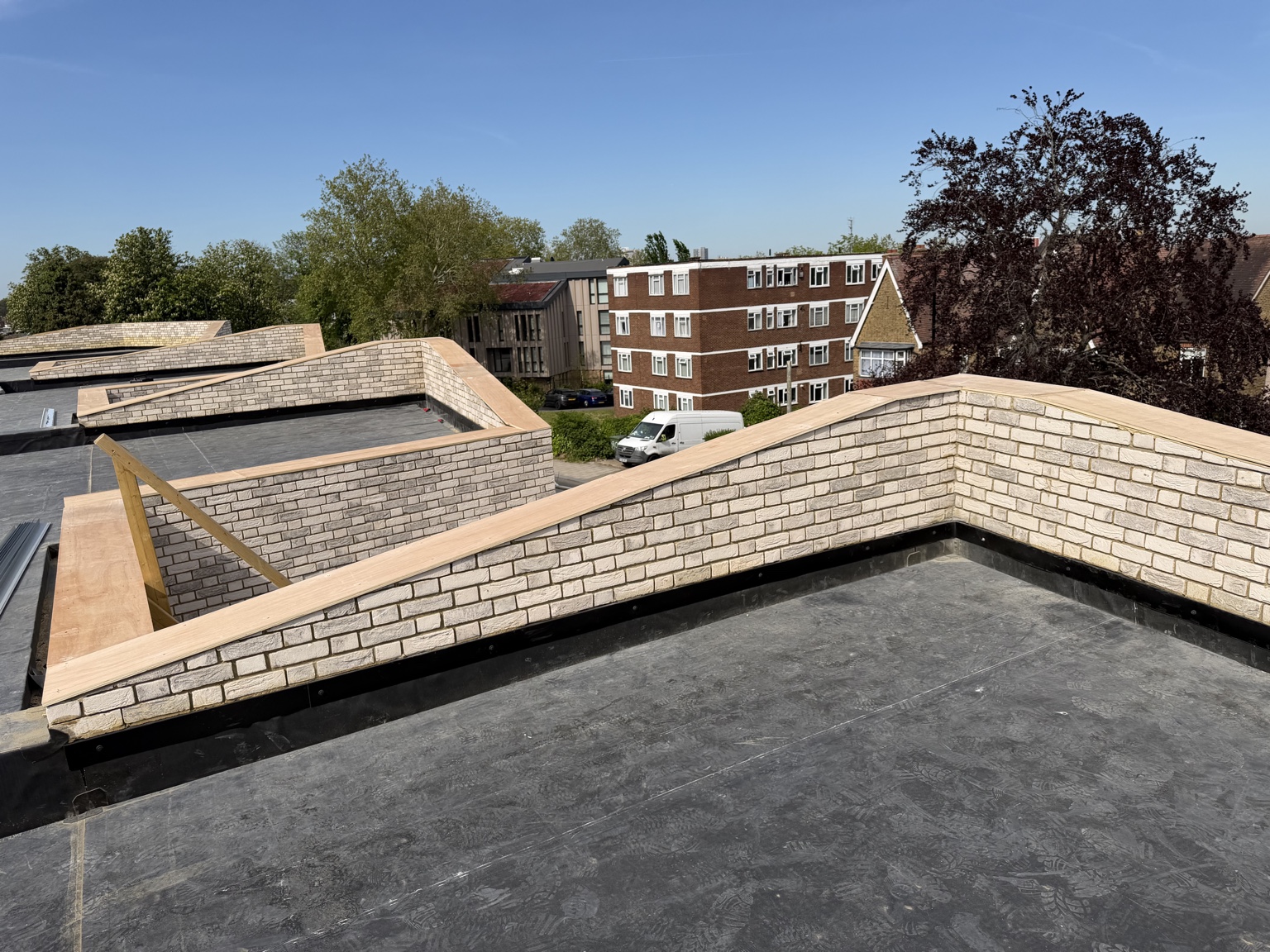 Finished brick parapet walls viewed across a flat roof